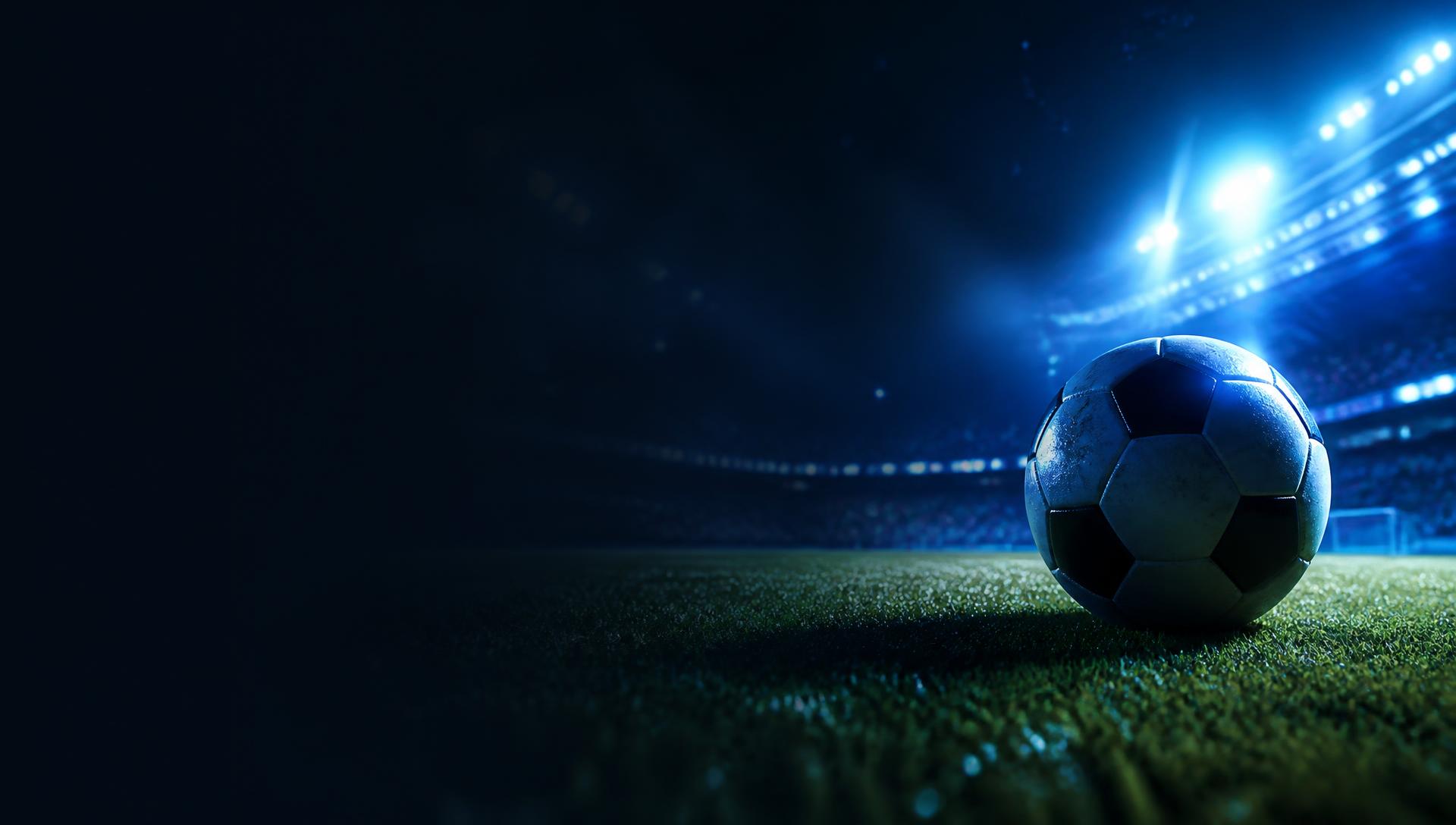 Estádio de futebol iluminado com bola no gramado